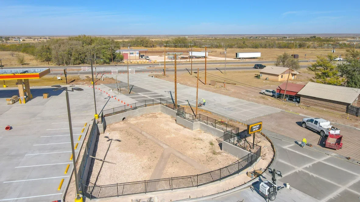 Aerial view of excavated site with concrete pads, metal railings, and graded earth