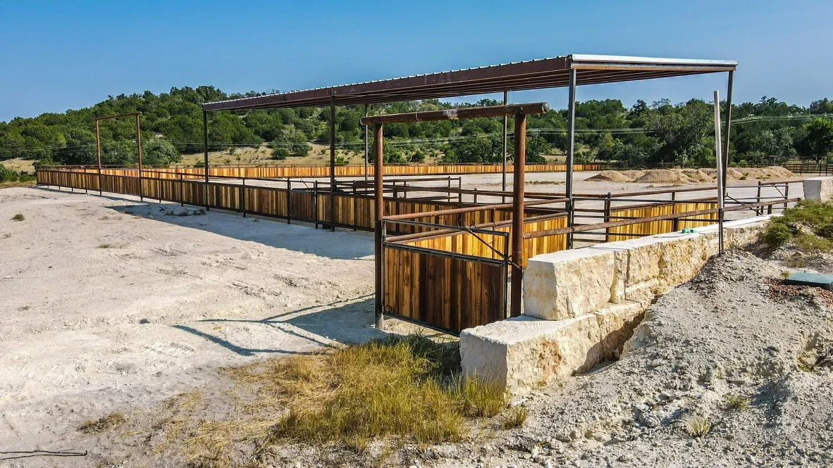 Metal frame livestock facility with wood panels, steel roof, and stone foundation walls