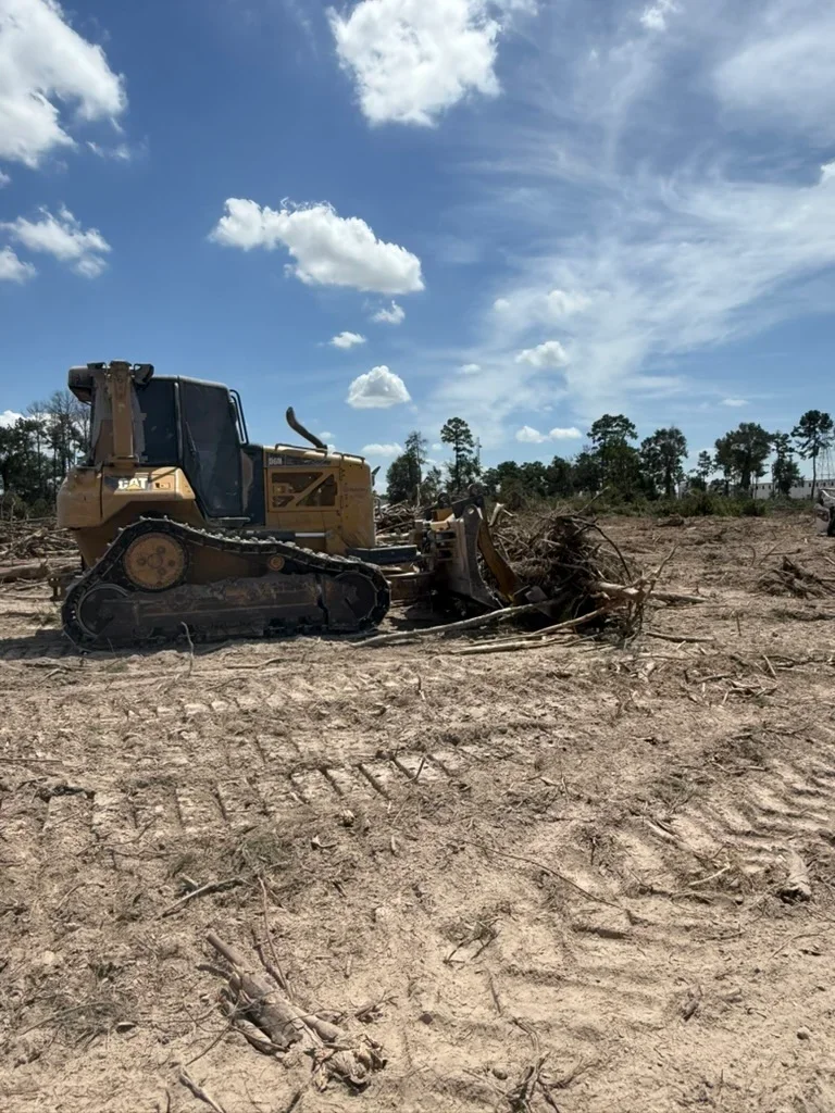 CAT track dozer clearing trees and debris from raw land with exposed soil