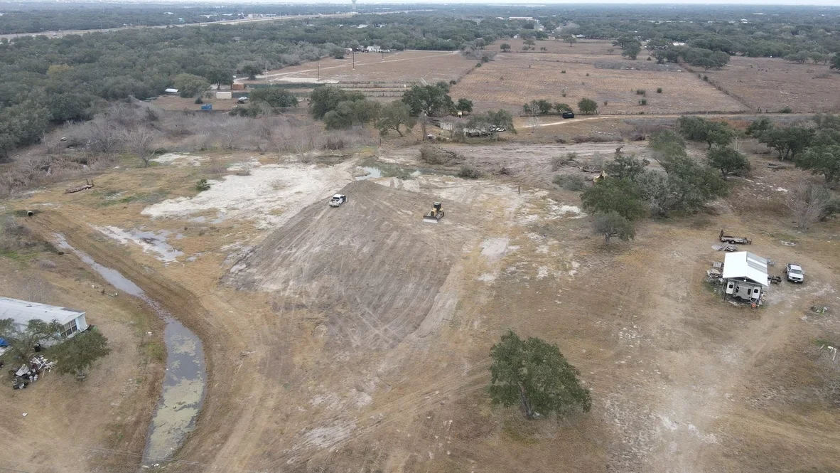 Aerial view of excavated and graded land with heavy equipment, cleared sections, and soil stockpiles