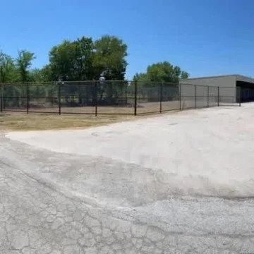 Graded dirt lot with chain-link fence enclosure and cleared ground surface