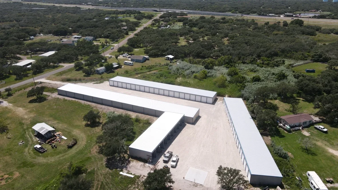 Aerial view of metal agricultural storage buildings with white roofing on prepared concrete pad and graded site