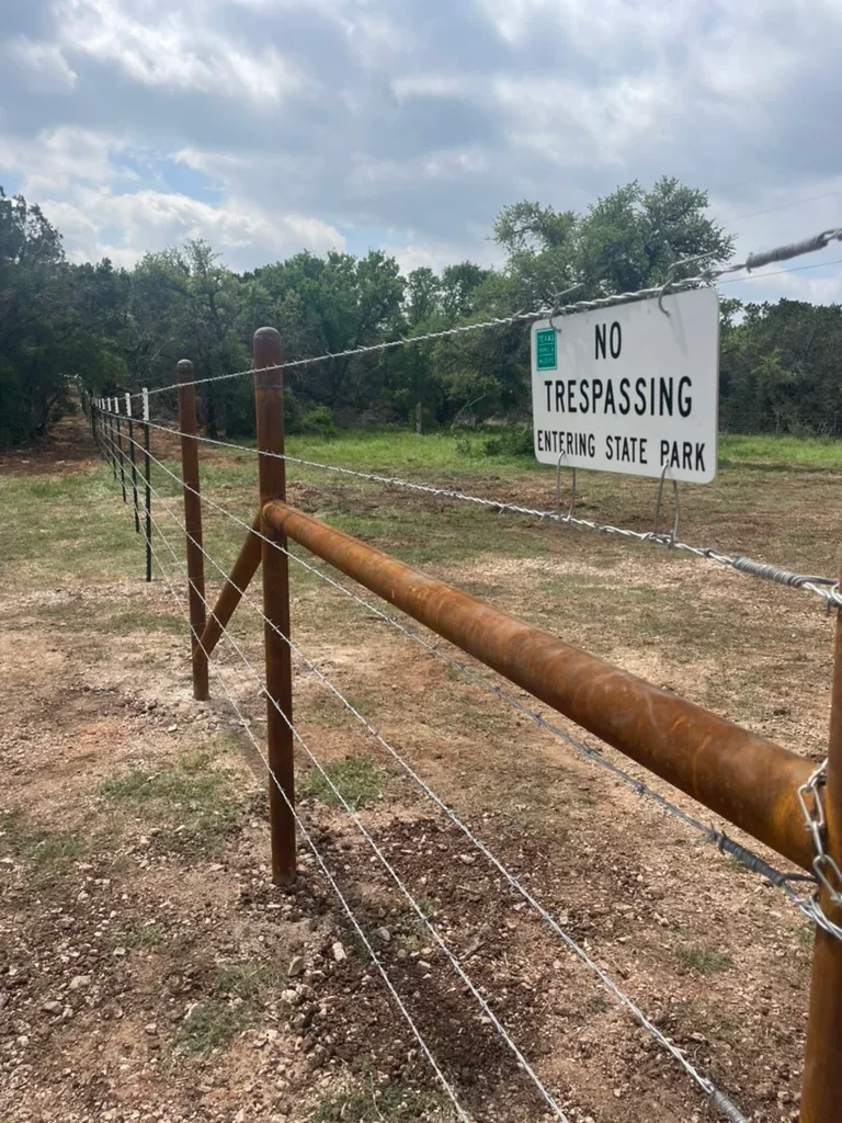 Wooden post and steel pipe ranch fence with wire fencing along property entrance