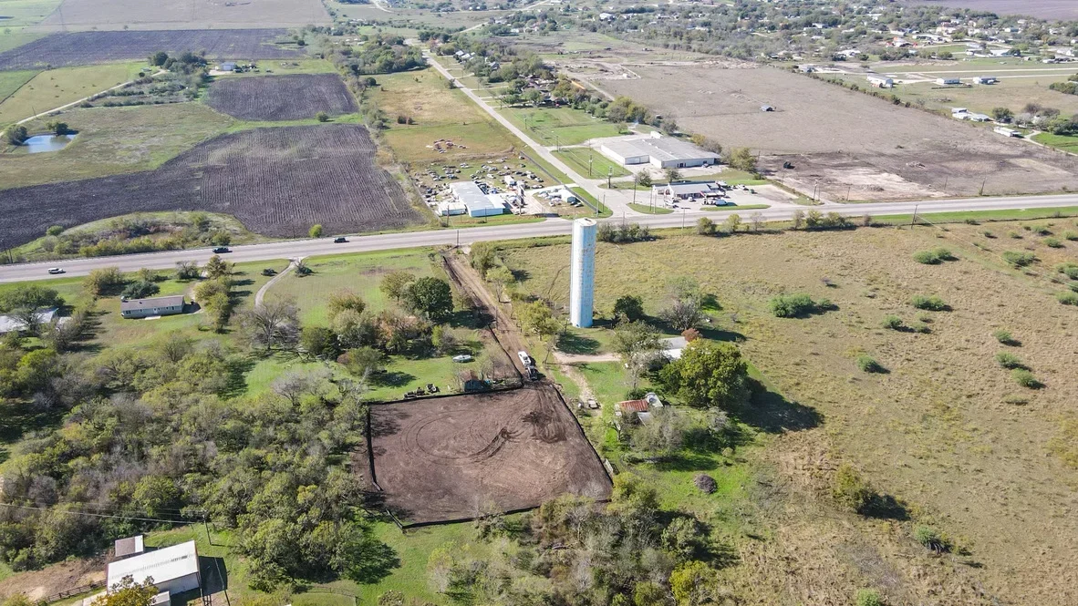 Aerial view of cleared agricultural land with grading marks, surrounding trees, and blue water tower