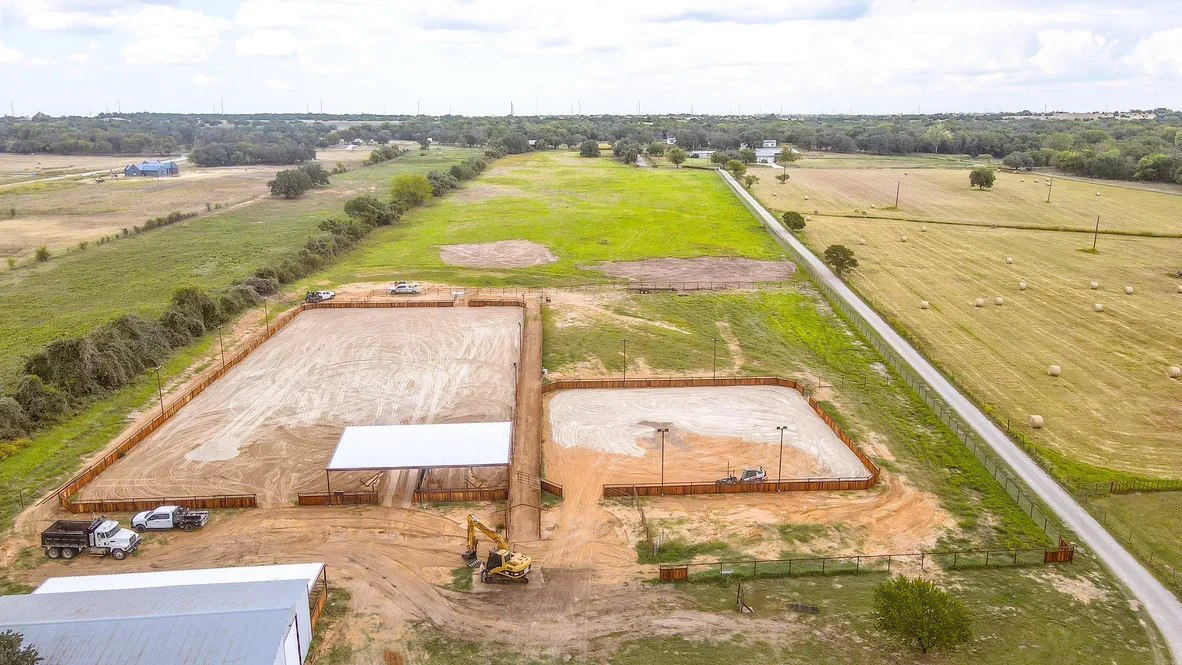 Aerial view of excavated retention ponds with clay lining, metal fencing, and graded earthwork on rural property
