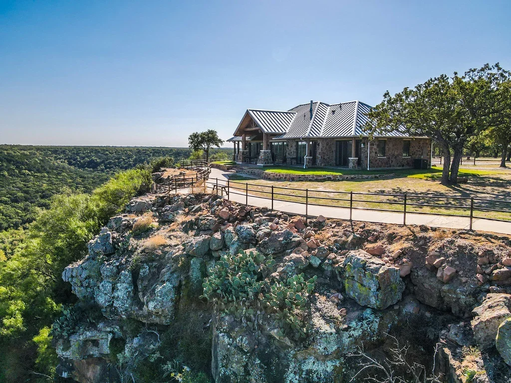 Excavated hilltop driveway with limestone rock removal and metal ranch-style fence installation