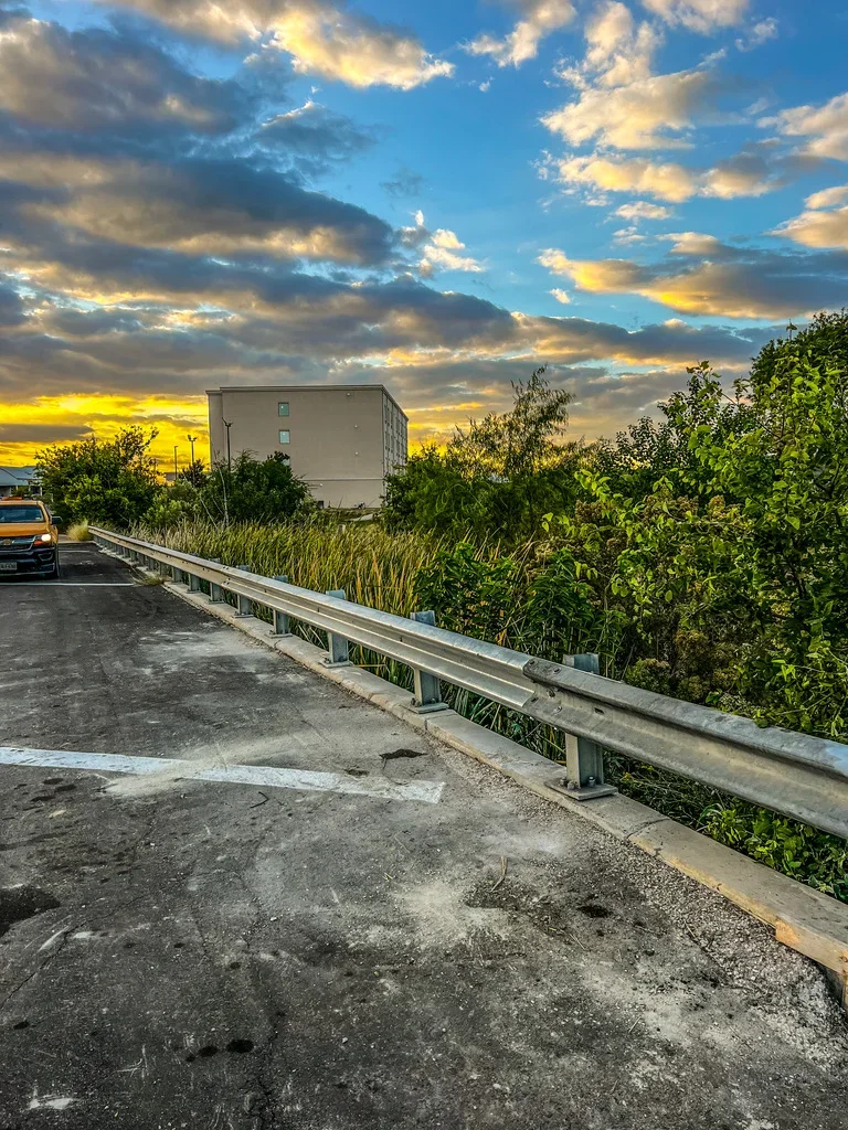 Concrete pad with galvanized steel guardrail along elevated roadway approach
