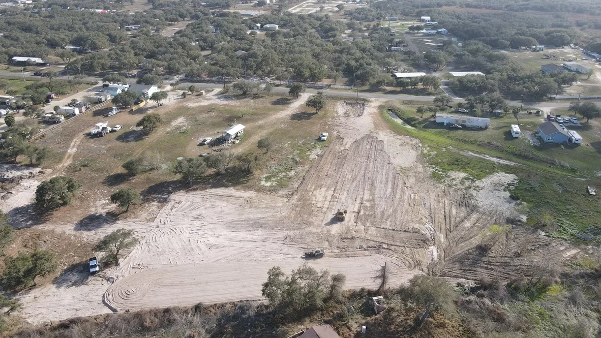 Aerial view of excavated site with graded earth, contoured slopes, and equipment on rural property