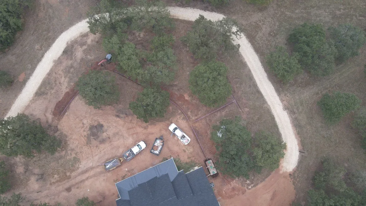 Aerial view of curved gravel driveway with crushed stone surface and site grading around metal building