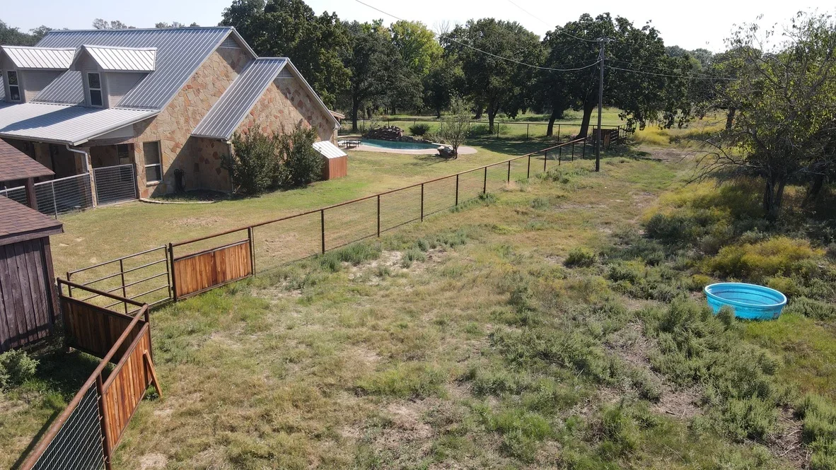 Steel pipe and wood panel ranch fencing with gates on rural property