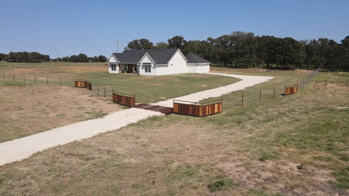 Concrete driveway and graded site pad for white residential home on rural acreage