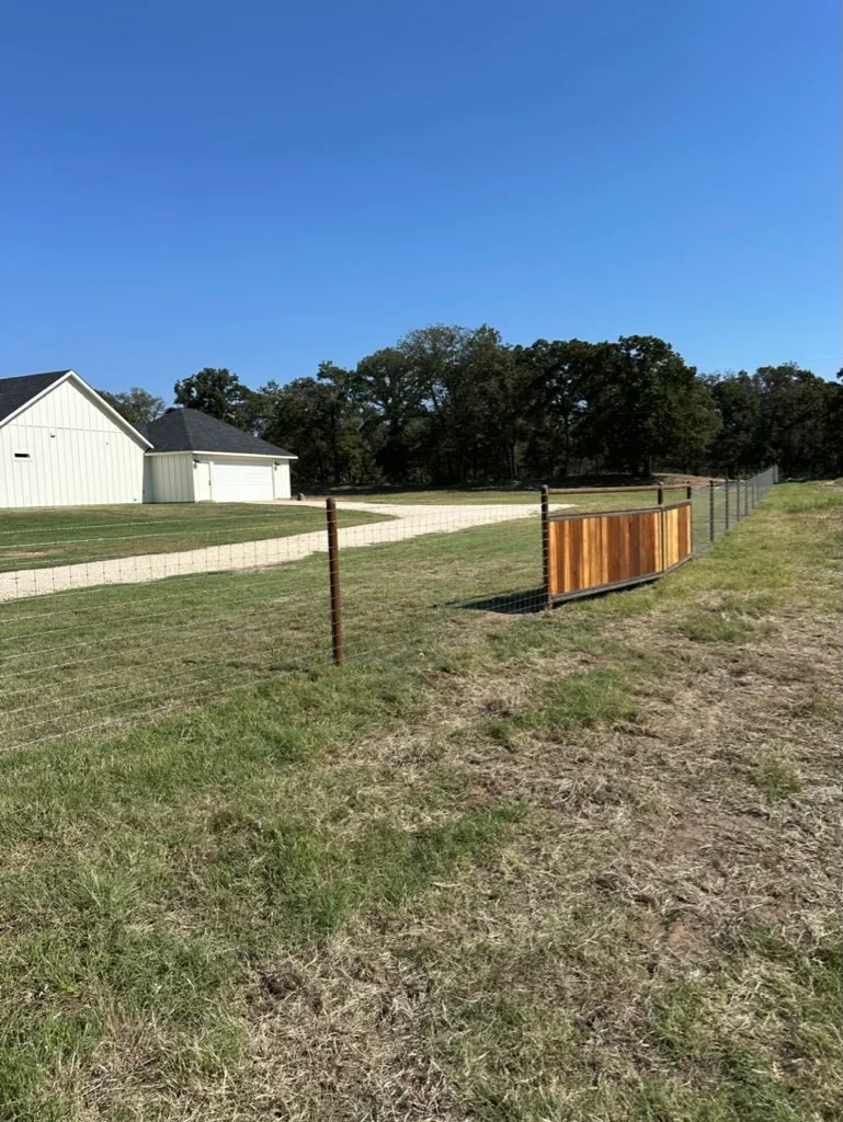 Metal post and corrugated panel ranch fencing with wire mesh on rural pastureland