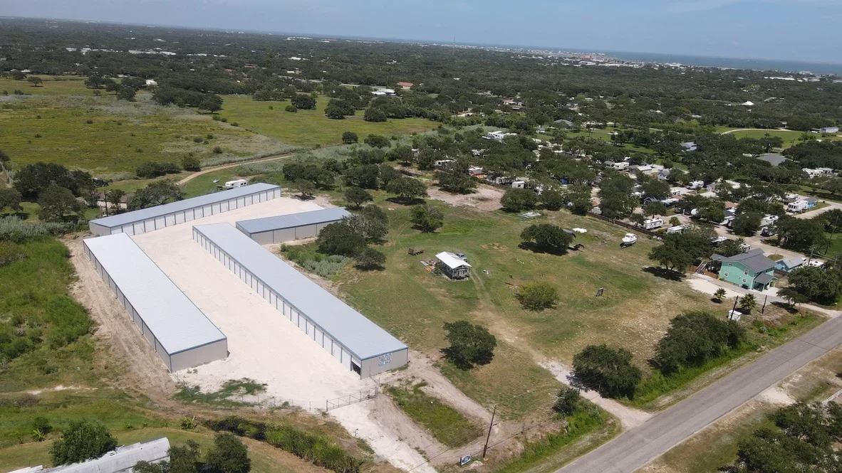 Aerial view of completed concrete pads and metal storage buildings on graded site with drainage