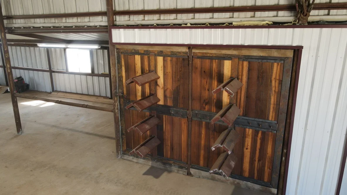 Two wooden livestock gates with steel frames and hardware mounted in metal corral structure