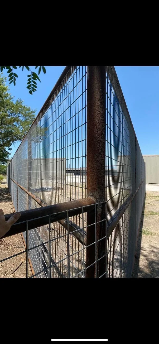 Steel livestock pen with wire mesh panels, central post, and swing gate