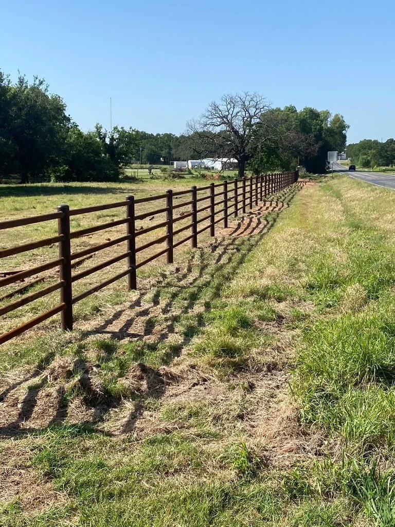Wooden ranch fence with horizontal rails installed along rural property entrance
