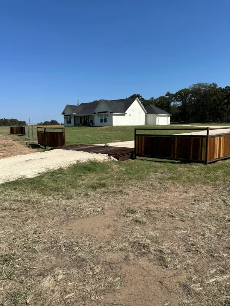Graded residential driveway with crushed stone base and metal ranch fencing on cleared property