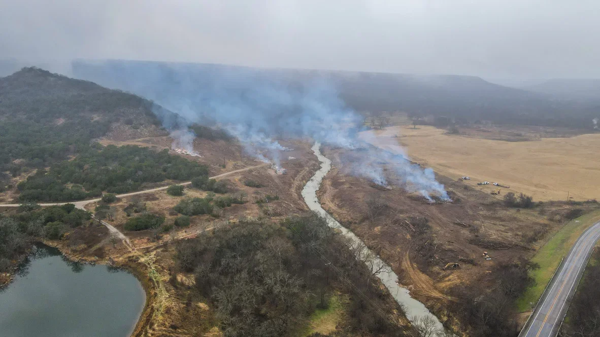 Aerial view of excavated land clearing along river with exposed soil and grading work
