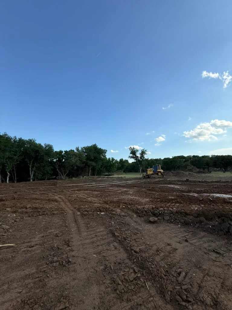 Cleared land with dozer, selective tree removal, graded soil preparation