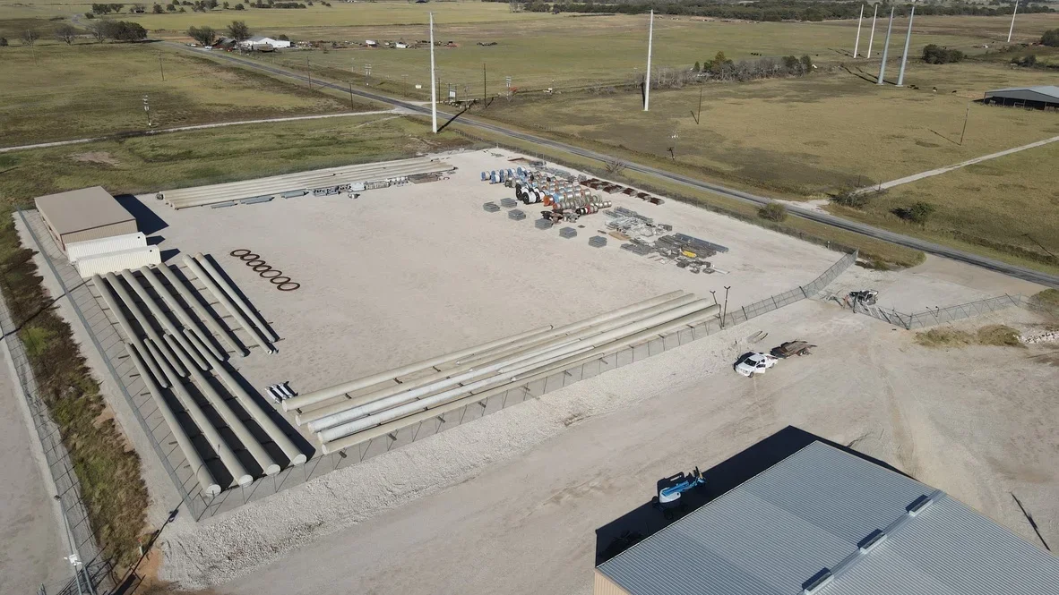 Aerial view of concrete pad with drainage channels, metal culverts, and gravel base