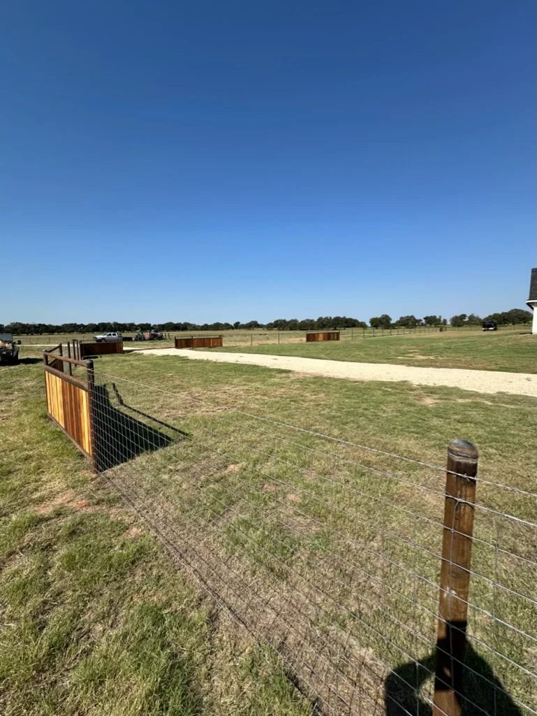 Gravel driveway with wire fencing, cleared and graded ranch property with pasture