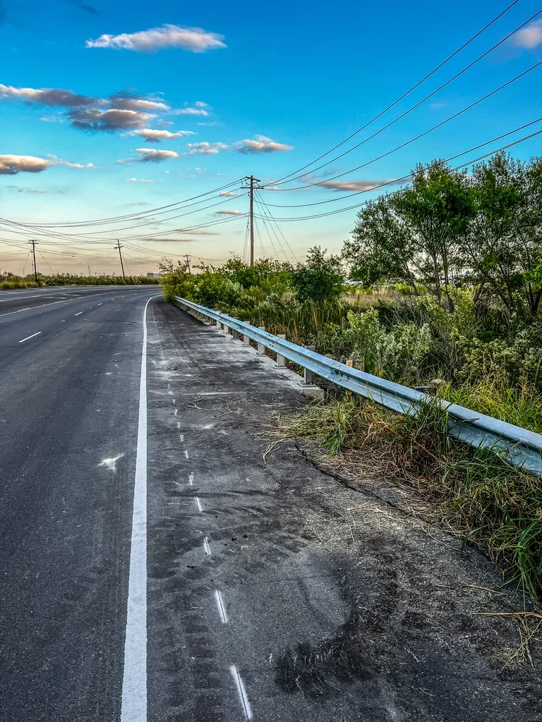 Galvanized steel guardrail installed along asphalt road with white line markings
