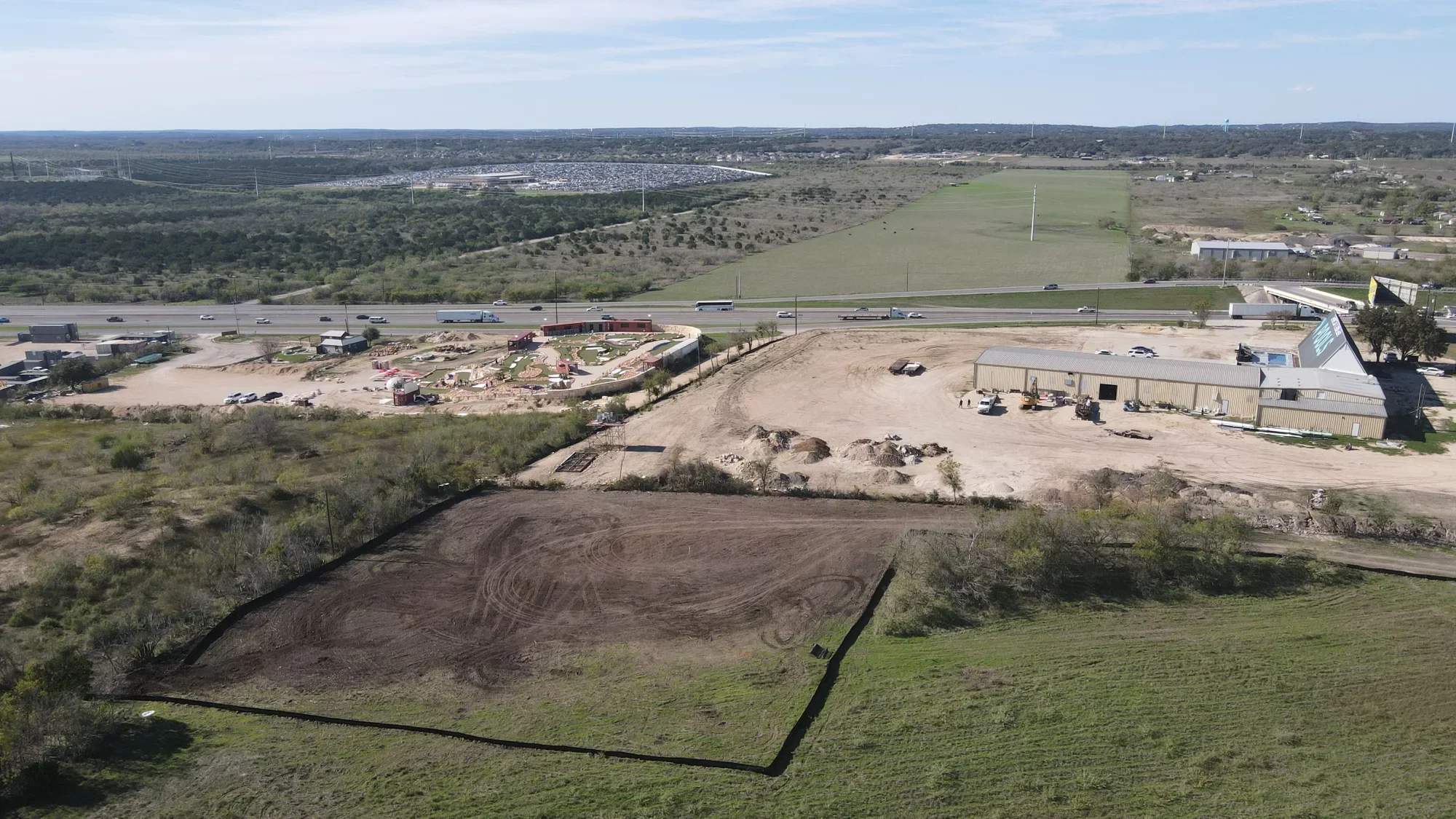 Aerial view of excavated commercial site with graded earth, material piles, and equipment