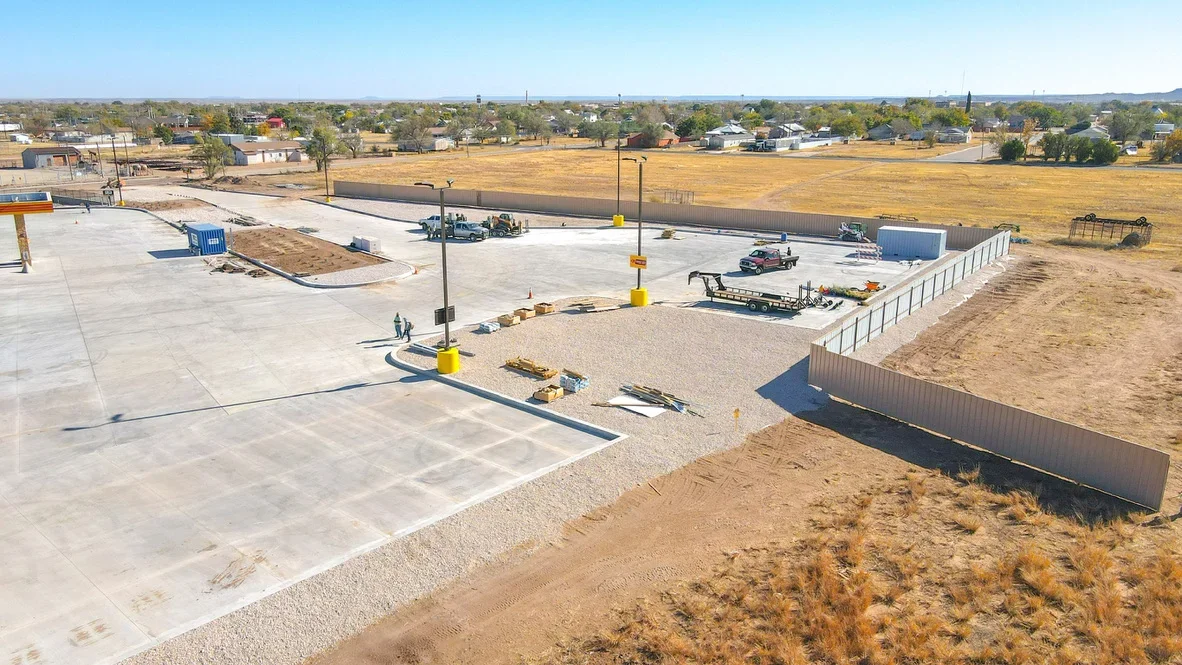 Aerial view of concrete pad, gravel base, and metal retaining wall on commercial excavation site