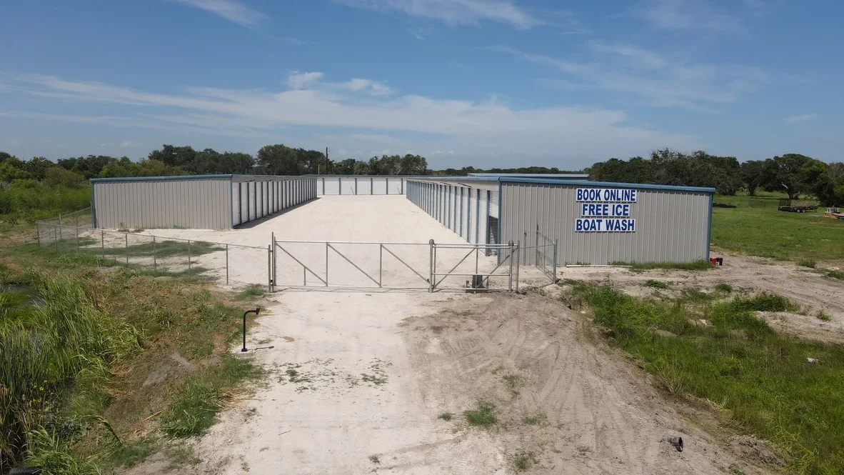 Metal storage buildings with concrete pad, metal gate, and graded dirt access road