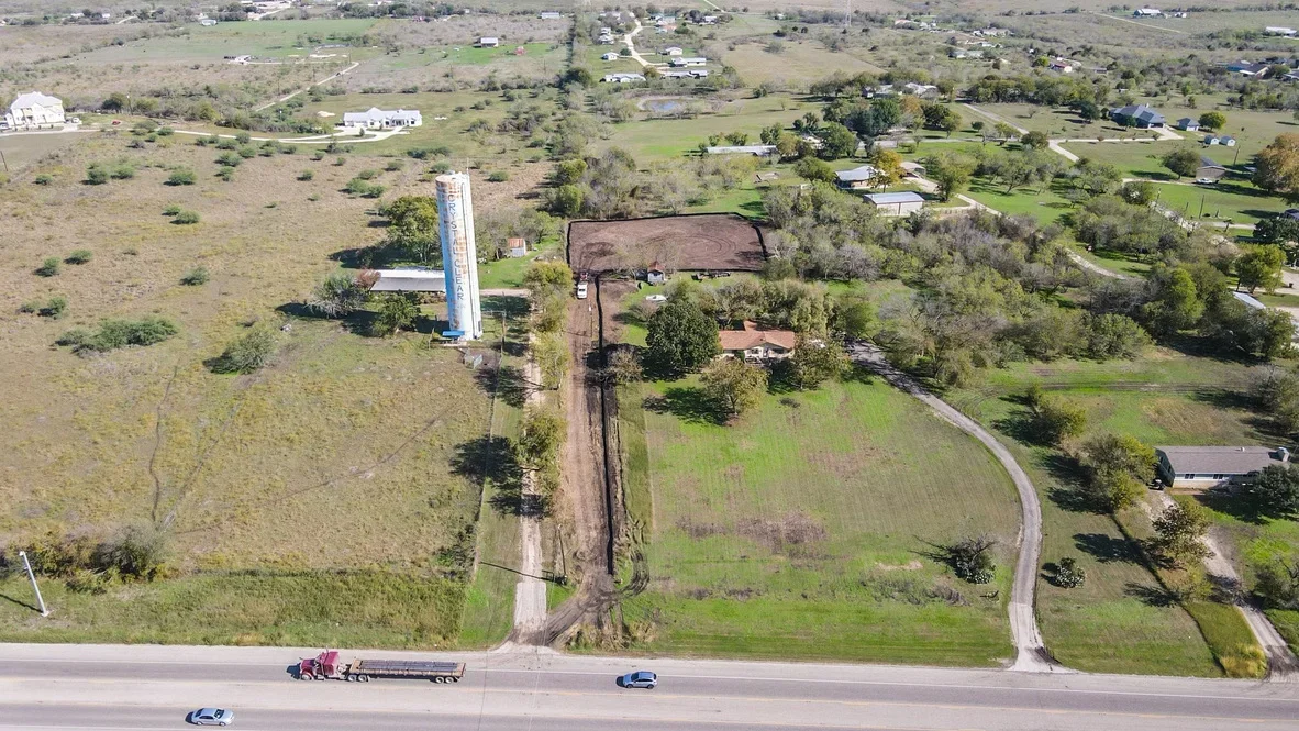 Aerial view of excavated driveway with graded dirt road and cleared access path through rural property