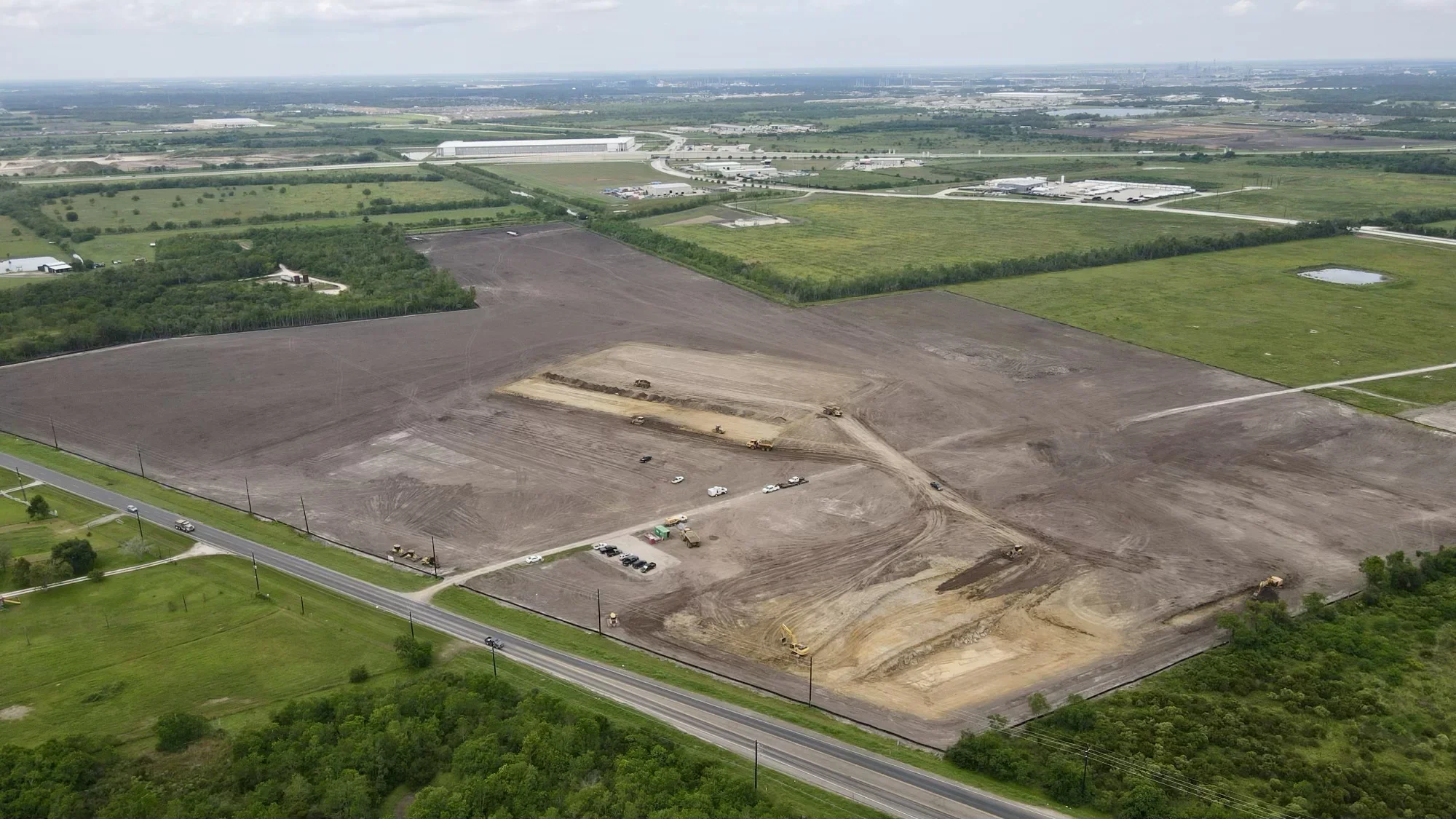 Aerial view of excavated commercial site with graded earth, heavy equipment, and access roads