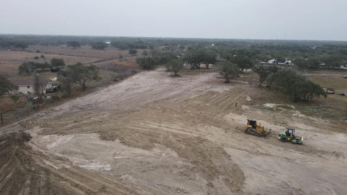 Aerial view of excavation site with dozer and grader equipment grading raw earth and soil