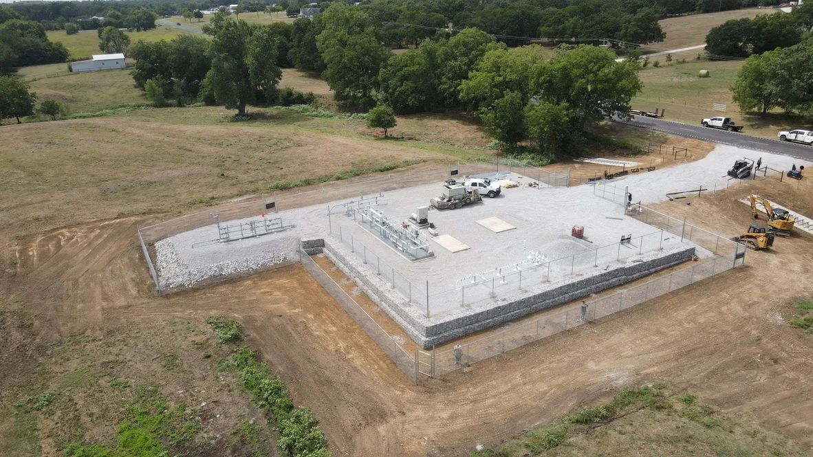 Aerial view of excavated foundation pad with concrete slab, retaining wall, and graded site preparation