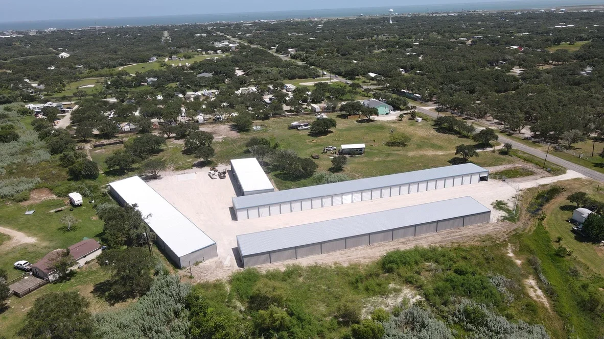 Aerial view of completed metal storage buildings with concrete pads and graded site on rural property