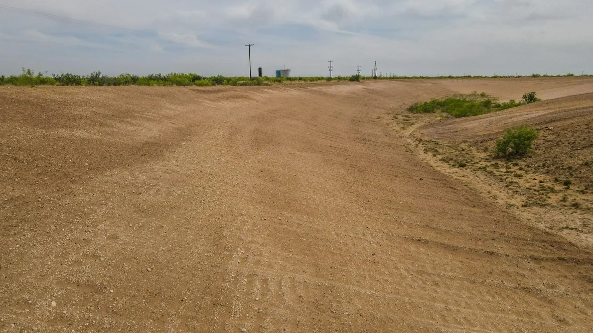 Graded dirt site with cut and fill slopes, cleared land preparation for construction