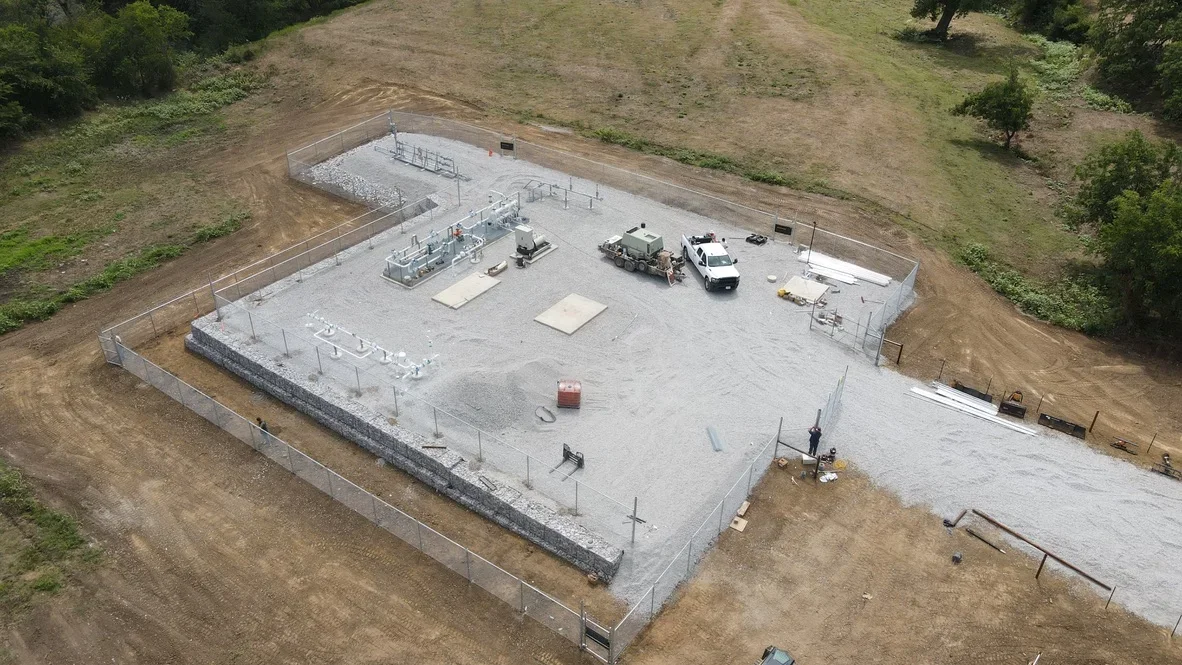 Aerial view of concrete foundation pad with retaining walls, drainage, and metal fencing on graded site